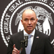 Utah Gov. Spencer Cox standing in front of the state seal.